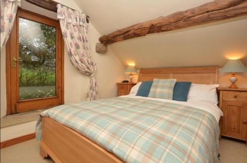a bedroom with a bed and a window at Cruck Cottage in Buxton