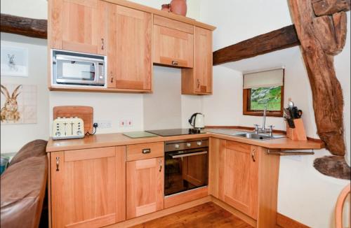 a kitchen with wooden cabinets and a microwave at Cruck Cottage in Buxton