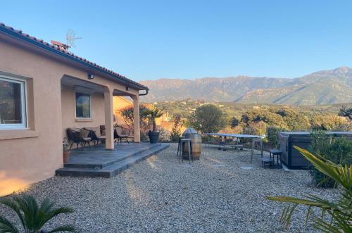 Cette maison dispose d'une terrasse avec une table et des chaises. dans l'établissement Villa Ghjuvan - Sea, Mountain & Spa, à Peri