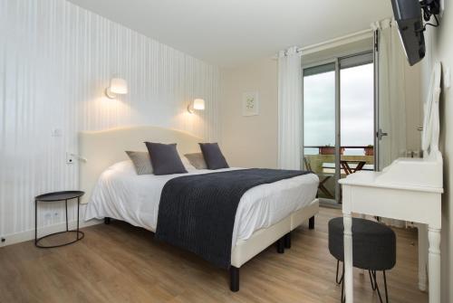a bedroom with a white bed and a white piano at Les Chants d'Ailes - Hôtel Face Mer in La Turballe