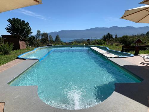 a swimming pool with blue water and an umbrella at Cabañas Copayapu in Pucón