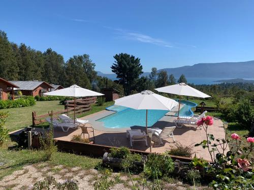 a swimming pool with umbrellas and chairs and a pool at Cabañas Copayapu in Pucón