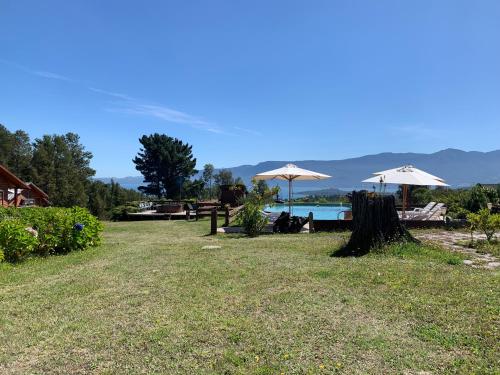 a park with chairs and umbrellas and a lake at Cabañas Copayapu in Pucón