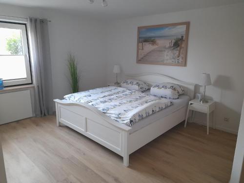 a white bed in a white bedroom with a window at Ferienwohnung Heimathafen Westensee in Westensee
