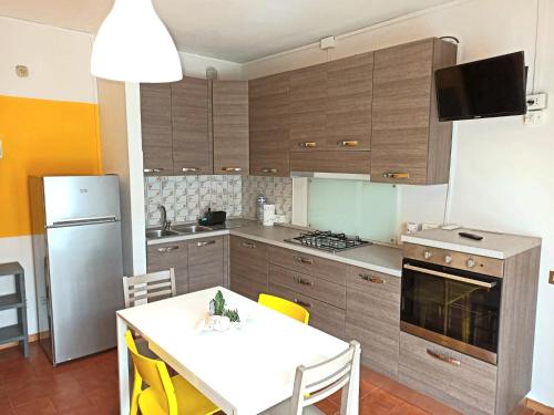 una cucina con tavolo bianco e una cucina con frigorifero di Casa Prati a Marina di Cecina