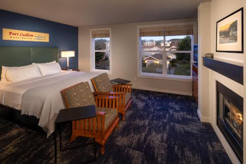 a bedroom with a bed and two chairs and a fireplace at Resort at Port Ludlow in Port Ludlow