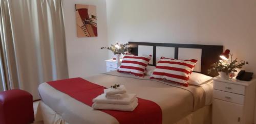 a bedroom with a bed with red and white pillows at Panacea Hotel in Villa General Belgrano