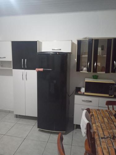 a kitchen with a black refrigerator and a microwave at Mongaguá House in Mongaguá