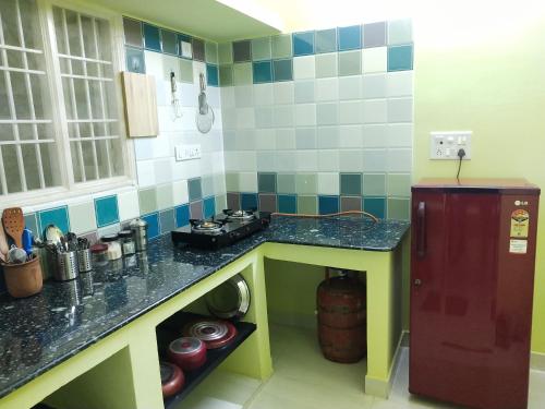 a small kitchen with a counter and a refrigerator at Villa Blossom, Near Serenity Beach in Pondicherry