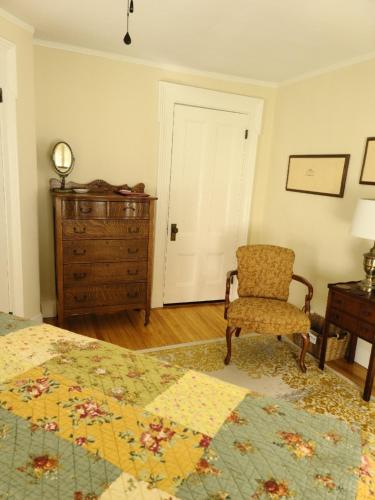 a bedroom with a bed and a chair and a dresser at Benjamin F. Packard House Bed and Breakfast in Bath