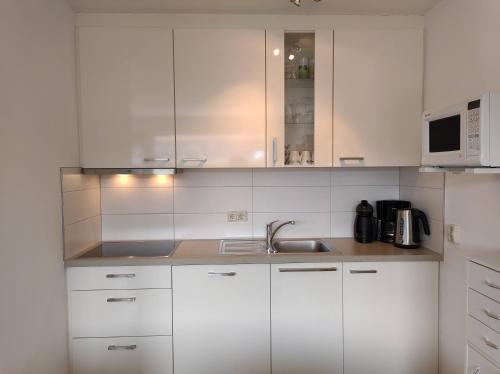 a white kitchen with a sink and a microwave at ZON Bed by the Sea in Westkapelle