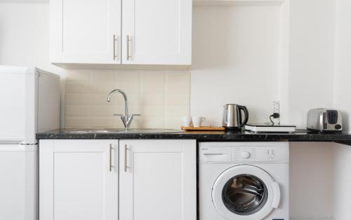 a white kitchen with a sink and a washing machine at Central Hoxton Shoreditch in London