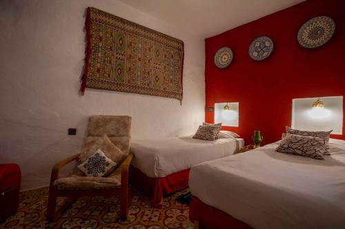 una habitación de hotel con 2 camas y una silla en Hotel Casa Miguel, en Chefchaouen