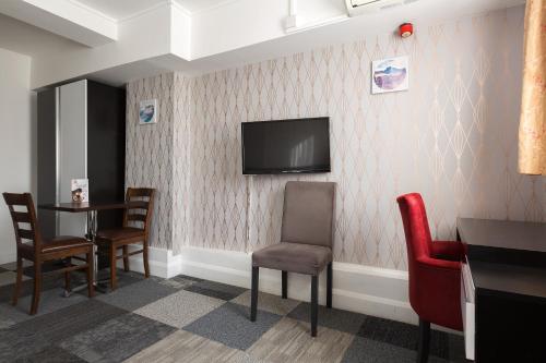 a waiting room with a tv and a table and chairs at Central Hoxton Shoreditch in London