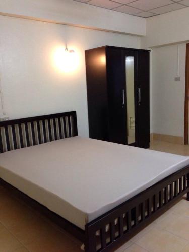 ein großes Bett in einem Zimmer mit einem schwarzen Schrank in der Unterkunft Jirapong apartment in Bangkok