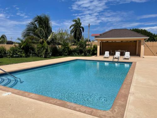 a swimming pool with two chairs and a gazebo at My Palm Retreat in Mammee Bay