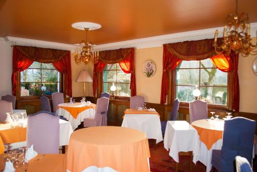 un comedor con mesas, sillas y ventanas en l'Auberge des Gourmets Hôtel Restaurant en Le Vaudioux