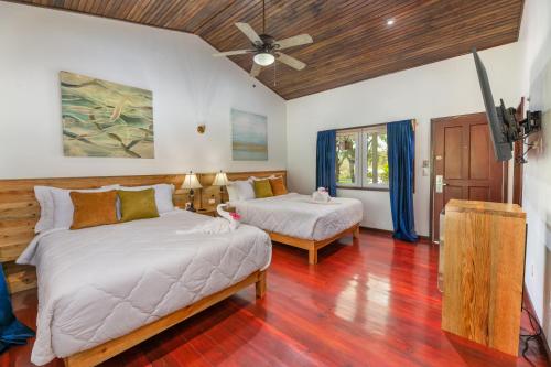a bedroom with two beds and a ceiling fan at Hotel and Dive Center Roatan Yacht Club in Roatan