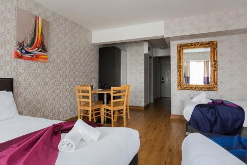 a room with two beds and a table and a mirror at Central Hoxton Shoreditch in London