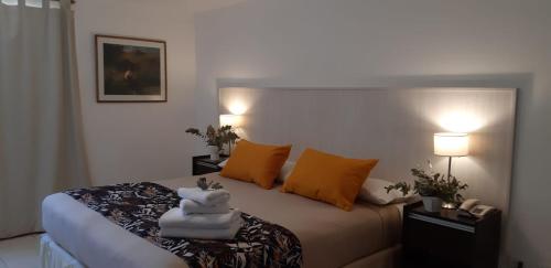 a bedroom with a bed with orange pillows and two lamps at Panacea Hotel in Villa General Belgrano