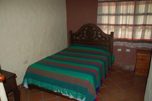 a bedroom with a bed with a colorful striped blanket at Cabañas Falconia in Mérida