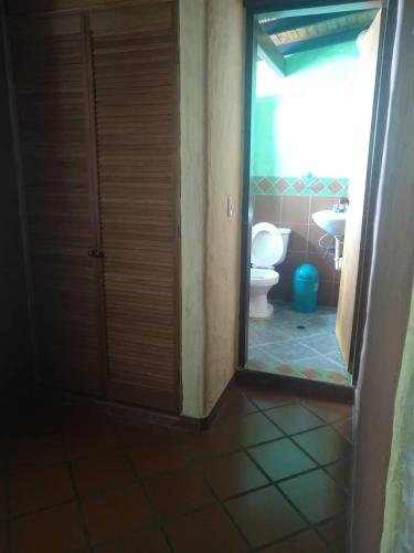 a bathroom with a toilet and a door with a mirror at Cabañas Falconia in Mérida