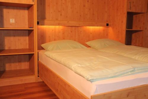 Bett in einem Zimmer mit Holzwänden und Regalen in der Unterkunft Ferienwohnung Schwarzwald in der Pension Glöcklehof in Todtnau