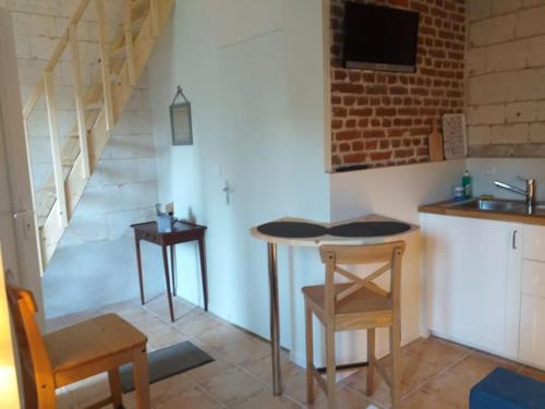 eine Küche mit einem Tisch, 2 Stühlen und einem Waschbecken in der Unterkunft Domaine d'Antigneul in Bours