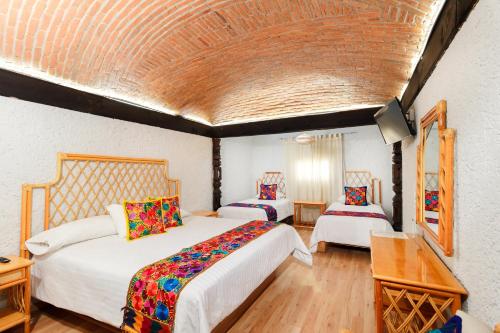 a hotel room with two beds and a table at Hotel Hacienda Montesinos in Morelia