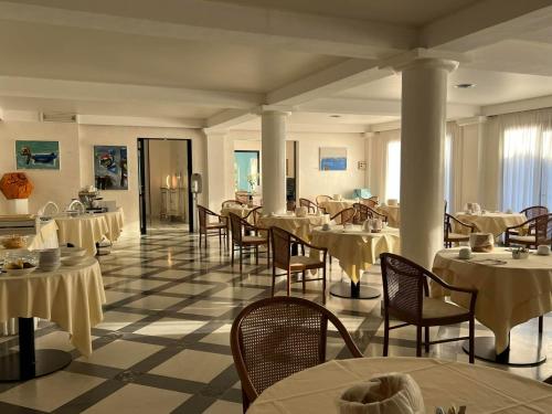 a restaurant with tables and chairs with white tables and chairsearcher at Arthotel Gabbiano Azzurro Due in Marciana Marina
