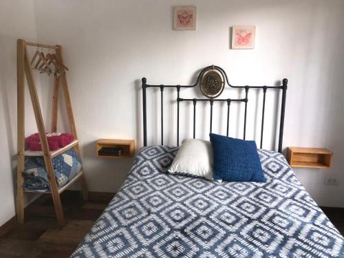 a bedroom with a bed with a blue and white comforter at PAZ EN LA CIUDAD, en el centro, con WIFI y cochera privada in San Antonio de Areco