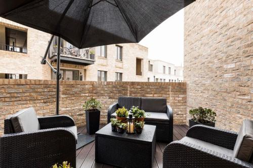 a patio with chairs and a table with an umbrella at Designer Penthouse Notting Hill with Terrace sleeps Five in London