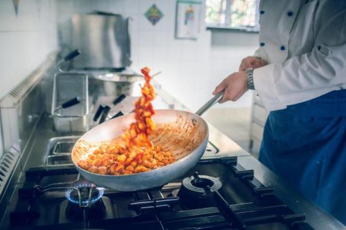 a person cooking food in a pan on a stove at Casale Guarracino in Sant'Agnello