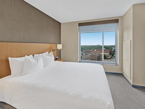 a large bed in a hotel room with a large window at Hyatt Place Champaign/Urbana in Champaign