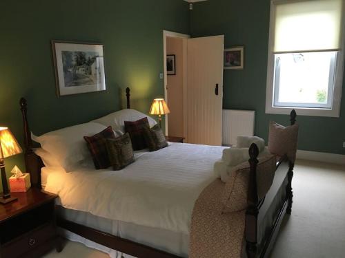 a bedroom with a large white bed with green walls at Viking Cottage in Arrochar