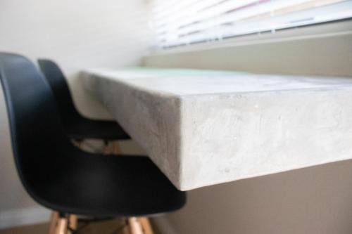 a concrete desk with two chairs and a window at Avodation in Walvis Bay