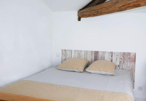 a bed in a room with two pillows on it at La Cabane in Penne-dʼAgenais