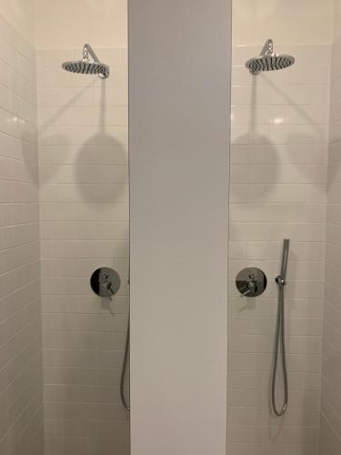 a shower with a glass door with a shower head at Lost Inn Porto Hostel in Porto