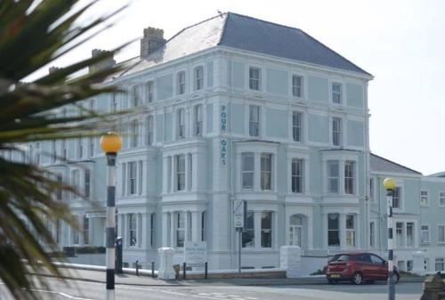 a white building with a car parked in front of it at Four Oaks Hotel in Llandudno