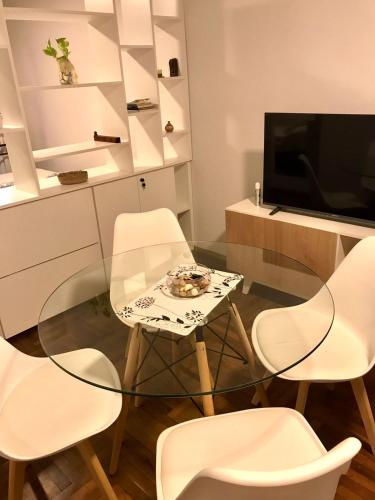 a glass table in a room with white chairs and a television at Monoambiente Centro in Cordoba