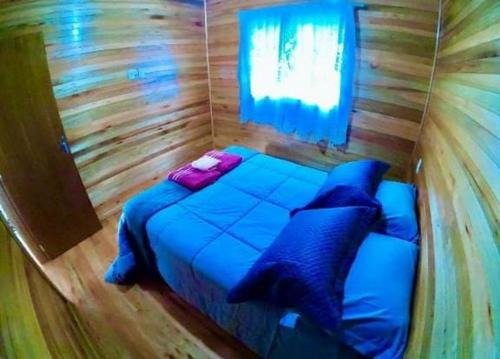 a bedroom with a blue bed in a wooden room at Casa de Campo Machado in Urubici