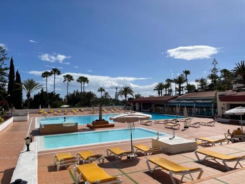 einen Pool mit gelben Stühlen und Tischen in der Unterkunft Exclusive & Elegant Luxury Stay with Stunning Ocean Views in San Bartolomé de Tirajana