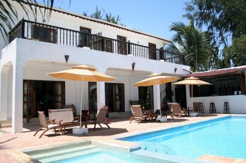 a villa with a swimming pool with chairs and umbrellas at Moonshine Uroa Boutique Hotel in Uroa