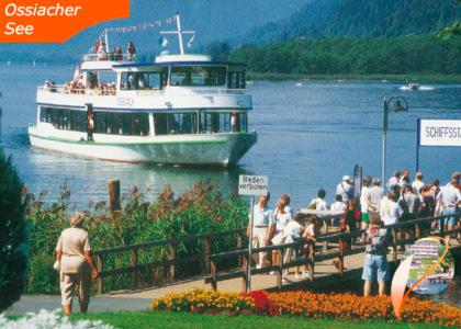 a group of people watching a boat in the water at Apartment Gerlitzen Ossiachersee - Haus Enzian - Urlaub am Berg in Treffen
