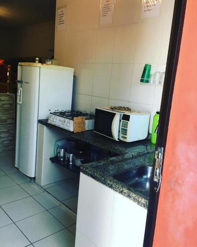 a kitchen with a refrigerator and a microwave at Pousada Astúrias in Ilha Comprida