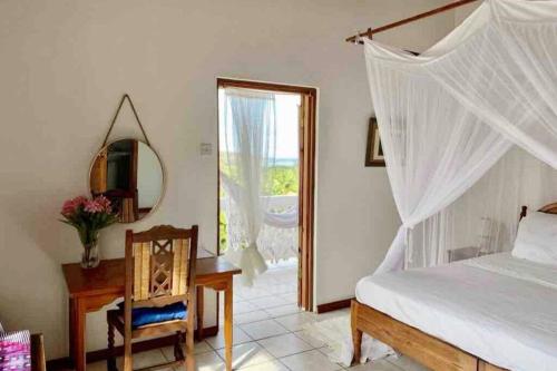 a bedroom with a bed and a table and a mirror at VILLA COLIBRI in Mon Repos