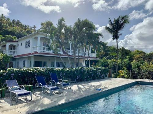 uma casa com cadeiras e uma piscina em VILLA COLIBRI em Mon Repos