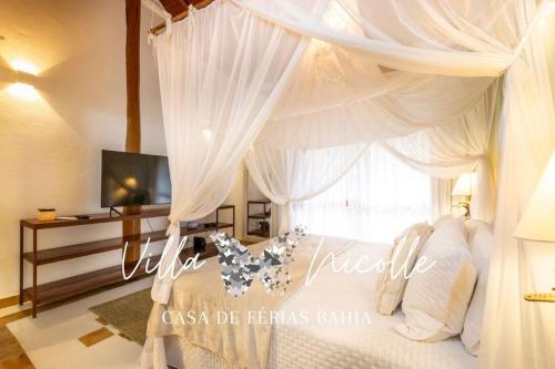 a bedroom with a canopy bed with white curtains at Villa Nicolle - Bahia - Praia do Espelho in Praia do Espelho