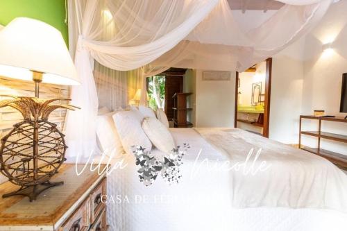 a bedroom with a white bed with a canopy at Villa Nicolle - Bahia - Praia do Espelho in Praia do Espelho