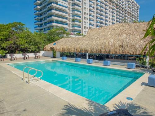 una piscina con techo de paja en Hotel Los Veleros Santa Marta, en Santa Marta